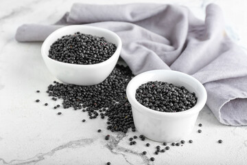 Bowls with black lentils on light background