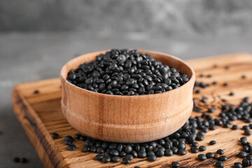 Fototapeta na wymiar Bowl with black lentils on grunge background