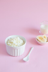 Rice porridge on vegetable milk with banana slices on pink minimal background