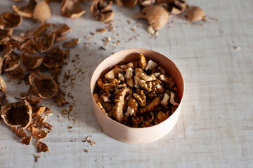 large horizontal photo. Walnut. Peeled walnut grains in an eco-friendly wooden jar. Dry shell. Harvest of nuts. White table. Vitamins. Healthy eating. ECO.