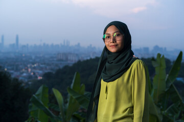 Portrait of young Asian woman during sunset, blue hour at hill view point, Bukit Ampang near Kuala Lumpur. Blurred background