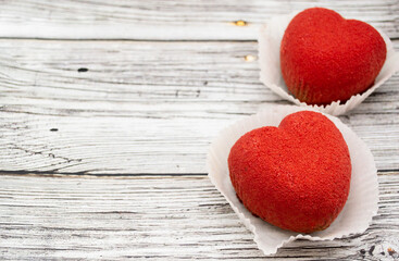 A bright red heart-shaped cakes on a wooden background. Copy space