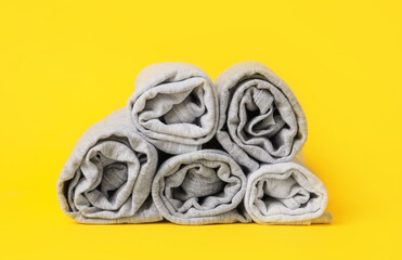 Rolled clean clothes on color background