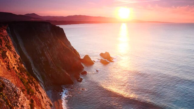 Sunset over rocky cliffs at Asturias coast in north Spain. View from Faro de Cabo Busto. Tourist attraction, place to visit.