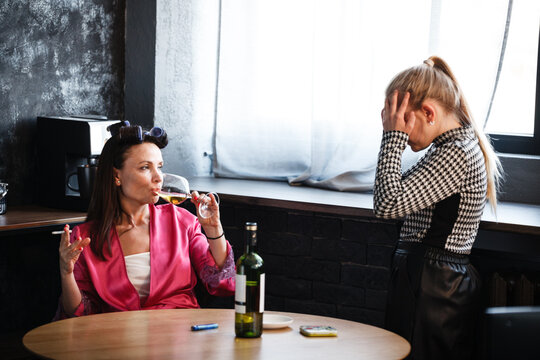 Alcoholism in family problem. Daughter aguring with her mother about drinking wine. Two people, woman and teenage girl quarrel in the kitchen. A depressed female is addicted to alcohol at home.