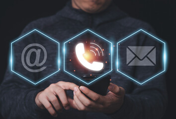 Businessman holding smartphone with business contact icons such as telephone address and email,...