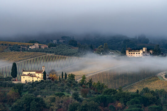 Castello di Gabbiano across a misty valley, church in foreground, San Casciano, Tuscany, Italy