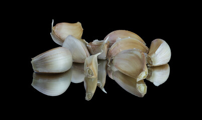A pile of garlic toes and the reflection of the garlic toes on the black background, a beautiful wallpaper of  fresh garlic toes