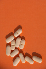 vitamin complex pills on colorful orange paper theme for fitness and sport and energy