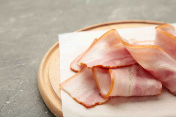 Fresh raw sliced bacon on the wooden cutting board on grey.