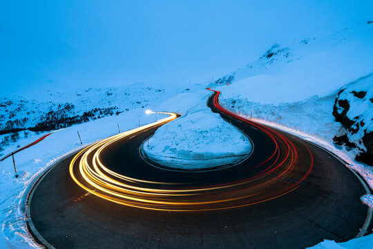 Car trail lights on bends of Bernina Pass road in winter, Val Poschiavo, canton of Graubunden, Engadin, Switzerland