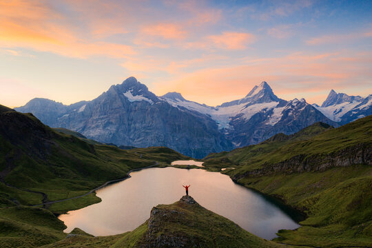 Cheerful hiker admiring Wetterhorn, Schreckhorn and Finsteraarhorn from Bachalpsee at dawn, Bernese Oberland, Switzerland