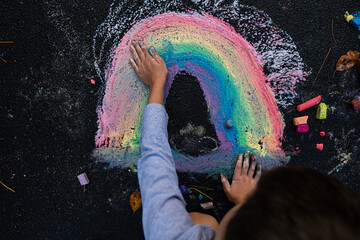 young boy blending a rainbow art with his hands and chalk