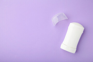 White antiperspirant deodorant on purple background. Skin care concept. copy space, top view