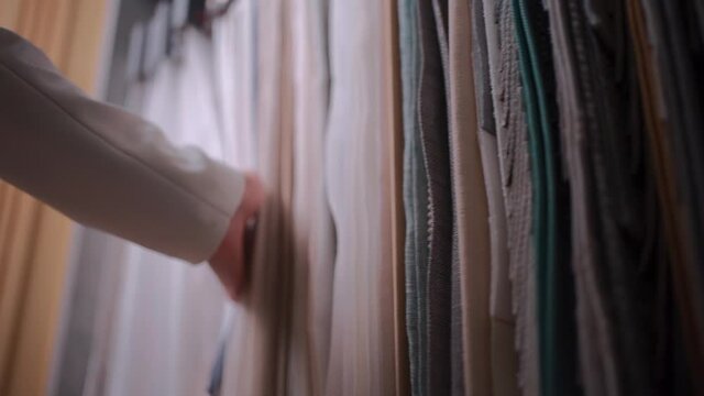 closeup of female hand choosing fabric cloth for curtain at showroom or shop
