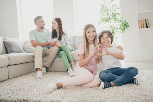 Full Size Photo Of Optimistic Family Mom Dad Two Kids Show Heart Hug Sit On Floor Sofa Wear T-shirts Trousers At Home