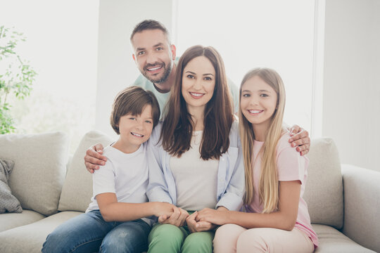 Photo portrait of cheerful family sitting together on sofa smiling keeping hand in hand