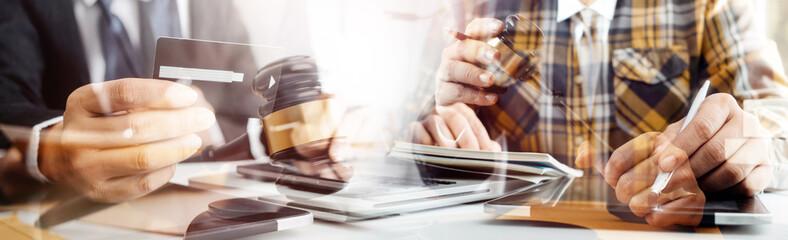 Justice and law concept.Male judge in a courtroom with the gavel, working with, computer and docking keyboard, eyeglasses, on table in morning light