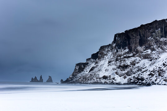 Black basalt sea stacks and snow covered black sand beach, Vik, Iceland, Polar Regions