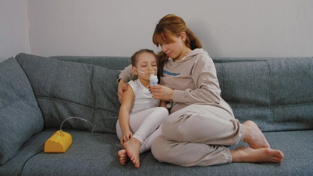 Mother gives her baby girl inhalation with medical nebulizer, sick bronchitis