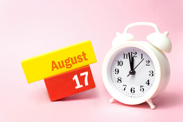 August 17th. Day 17 of month, Calendar date.White alarm clock on pastel pink background. Summer...