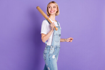 Profile photo of nice optimistic short hairdo blond lady hold bat wear white t-shirt overall isolated on violet background