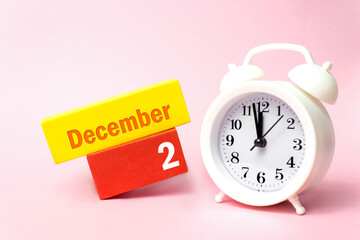 December 2nd. Day 2 of month, Calendar date.White alarm clock on pastel pink background. Winter month, day of the year concept.