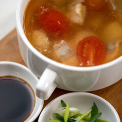Pot of meat soup or broth with tomatoes, sauce and salad. Close up shot. Top view. Nutritious wholesome food. Delicious and healthy lunch or dinner.