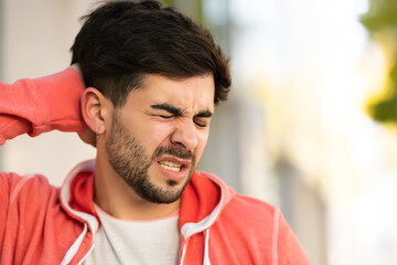 Obraz premium Young man suffering headache outdoors.