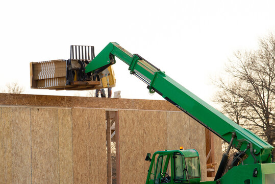 forklift at a construction site of a plywood house wood new frame