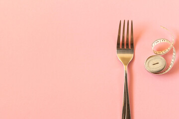 Measuring tape and plug on pink background. The concept of dieting.