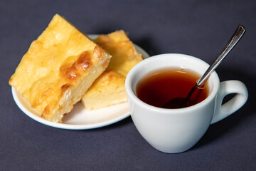 Tea in a white cup with a curd casserole on a saucer. Breakfast. Close-up. Selective focus.