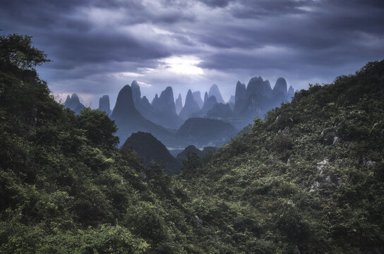 Yangshuo mountains with dark clouds framed by hills, Yangshuo, Guangxi, China