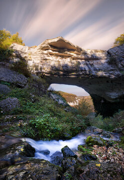 Waterfall flowing below Veja bridge, a huge natural arch in Lessinia, Veneto, Italy