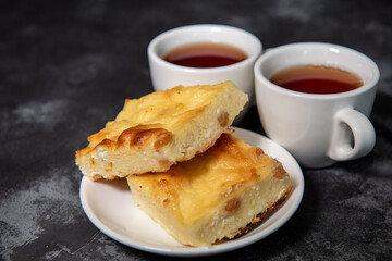Two cups with tea, cottage cheese casserole on a saucer. Breakfast. Close-up. Selective focus.