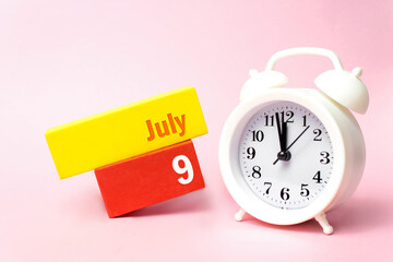 July 9th. Day 9 of month, Calendar date.White alarm clock on pastel pink background. Summer month,...