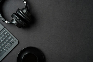 Top view modern office desk with headphones, cup of coffee, laptop computer on black leather...