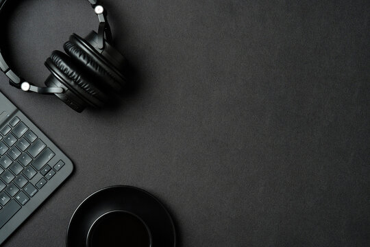 Top View Modern Office Desk With Headphones, Cup Of Coffee, Laptop Computer On Black Leather Background. Flat Lay Sound Producer Workspace.