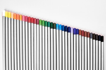Colored pencils lined up in a row on a pink background.
