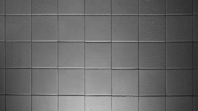 The texture of light gray square glossy ceramic tiles with water drops. Bottom soft lighting.