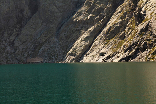 Clean and turquoise water of a high-altitude lake, surrounded by the rocky nad silent mountains in summer, landscape of the Aragonese Pyrenees, Huesca, in the area of the Posets-Maladeta Natural Park.