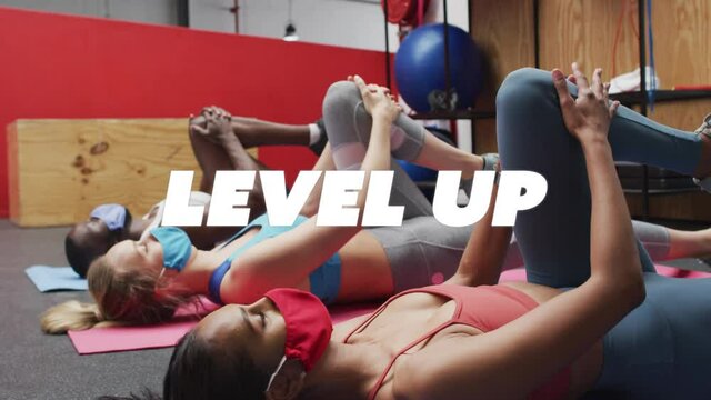 Level up text against fit people wearing face masks performing stretching exercise at gym