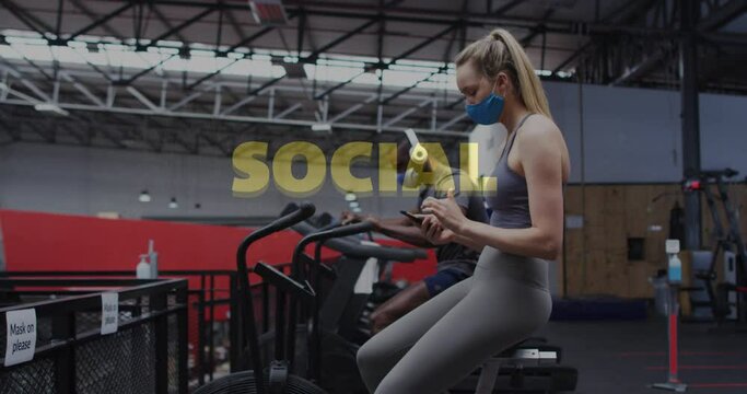 Social distancing text against caucasian woman wearing face mask using smartphone at gym