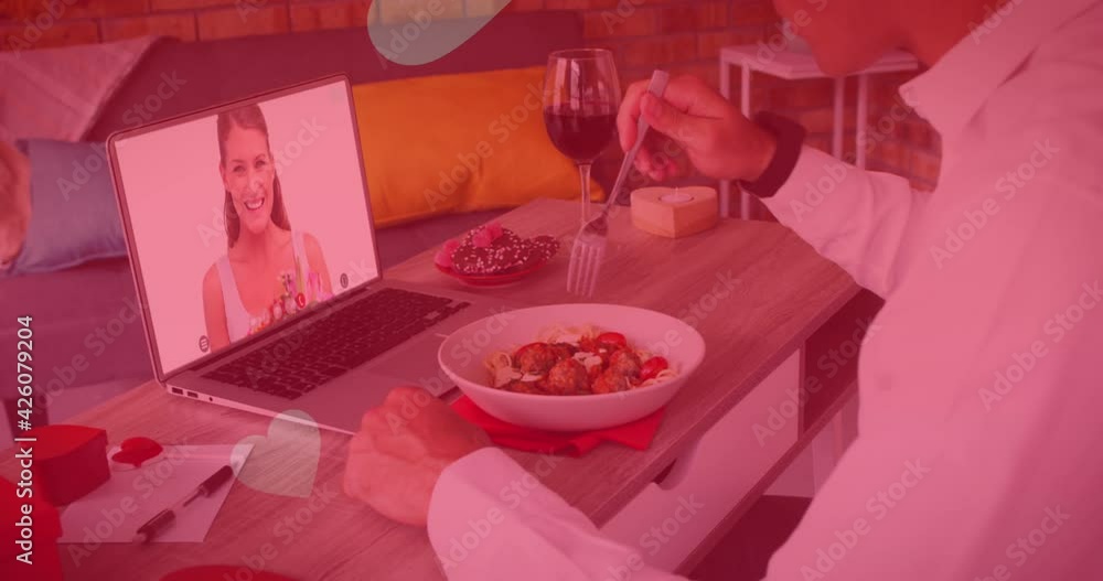 Poster multiple heart icons floating over caucasian man having lunch while having a video call on laptop
