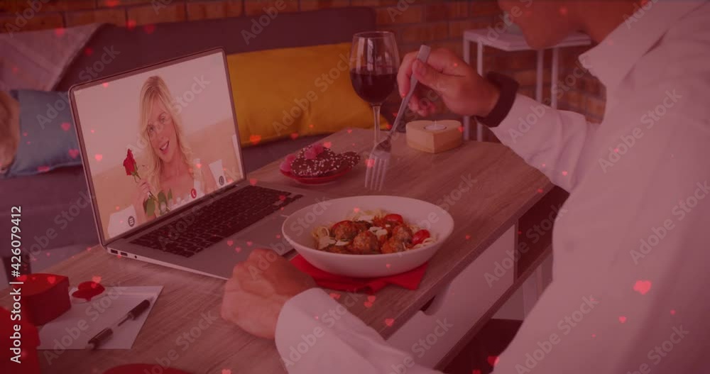 Poster red heart icons floating over caucasian man having lunch while having a video call on laptop