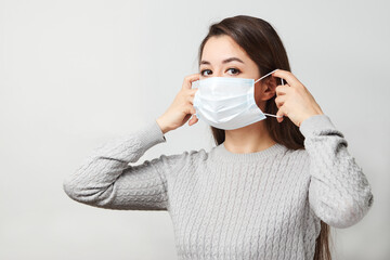 Young woman wearing medical mask, white background.