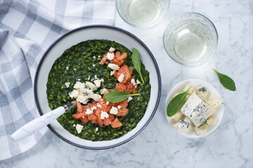 Above view of spinach risotto with gorgonzola and tomato tartare, horizontal shot over light-grey marble background