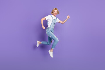 Fototapeta na wymiar Full size profile photo of nice optimistic short hairdo blond lady run wear white t-shirt overall isolated on violet background