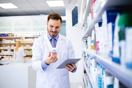 Pharmacist working in drug store and checking medicine expiration date on tablet computer.