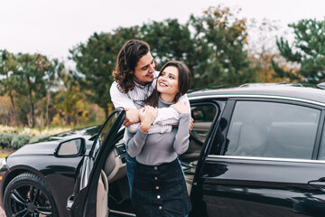 Happy young couple near their car on the street. Car loan, new car